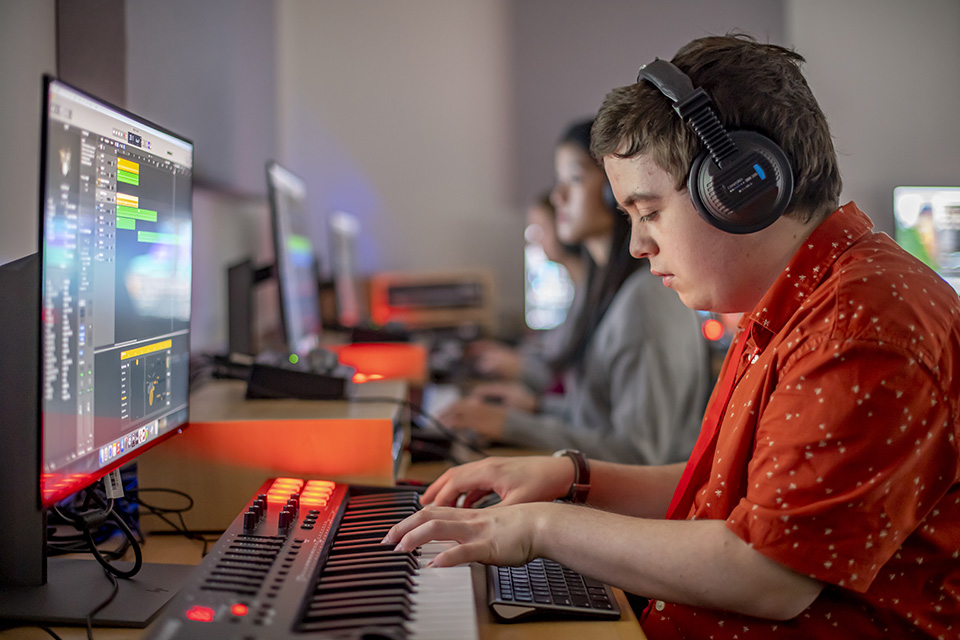 A student using a computer and keyboard to produce his composition